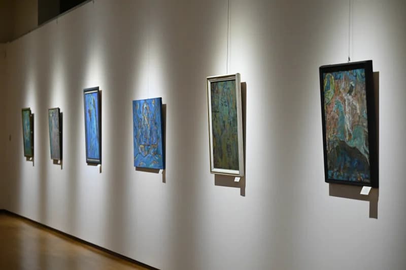Paintings hang on white gallery wall