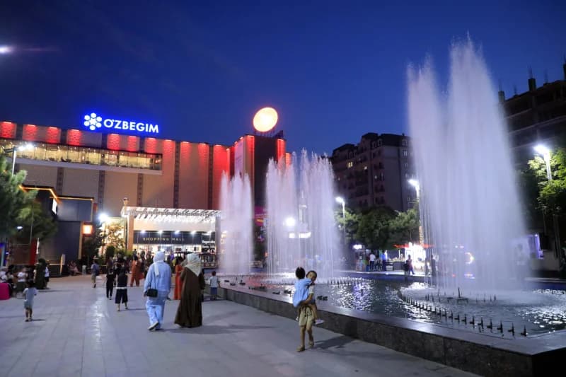 People walking on a city plaza with fountains