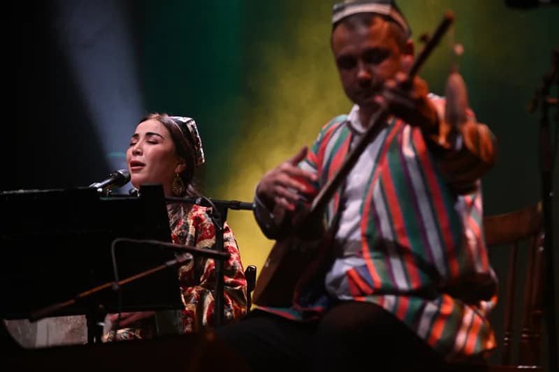 Anʼanaviy libosdagi ijrochilar sahnada musiqa ijro etadilar.