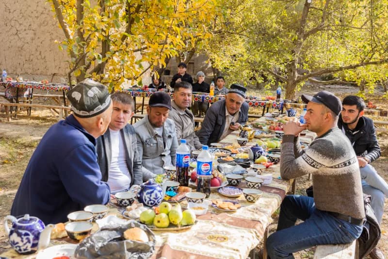 People gathered for an outdoor meal at tables set in a rural garden