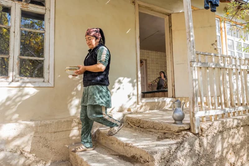 Person walking down outdoor steps carrying plates near a house