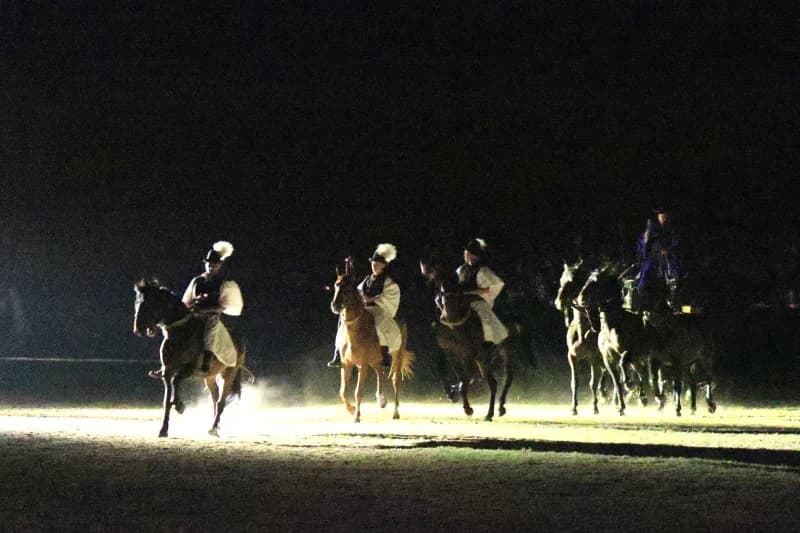 People riding horses outdoors at night