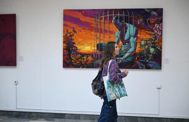 Woman walking past a large colorful painting in a gallery