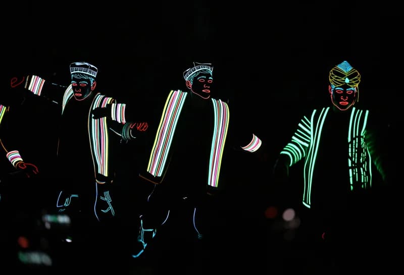 Performers in illuminated outline costumes during a night show