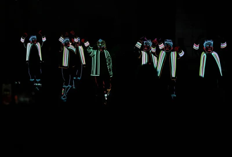 Performers in illuminated costumes on stage during night show
