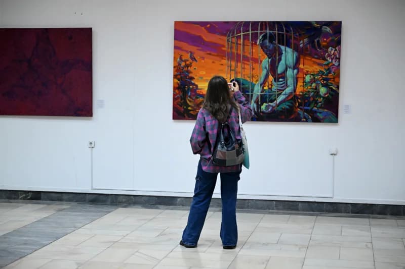Visitor photographing artwork in an exhibition space