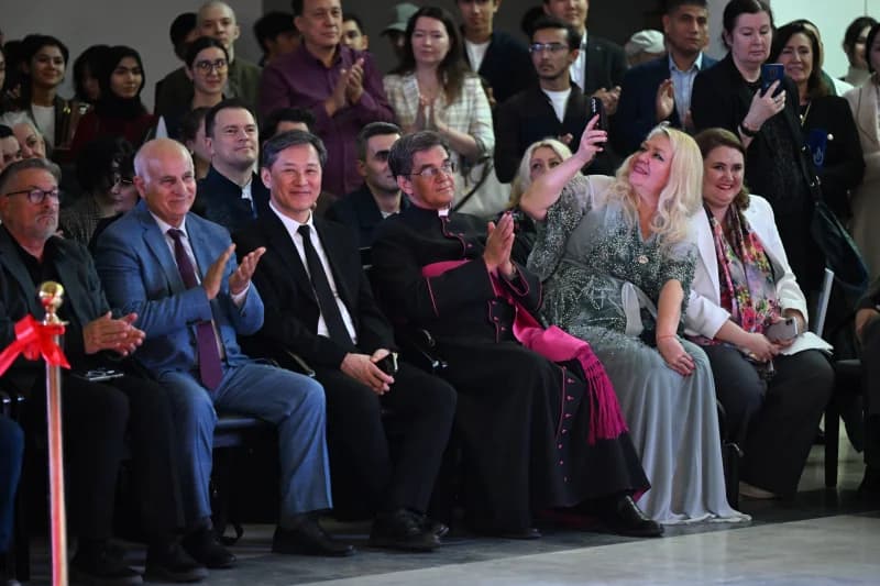People gathered indoors applauding and taking photos