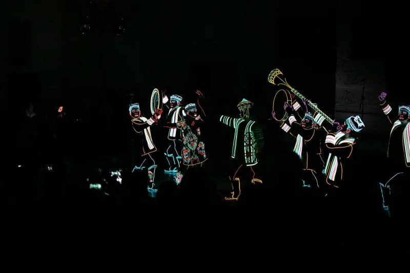 Performers in illuminated costumes on stage